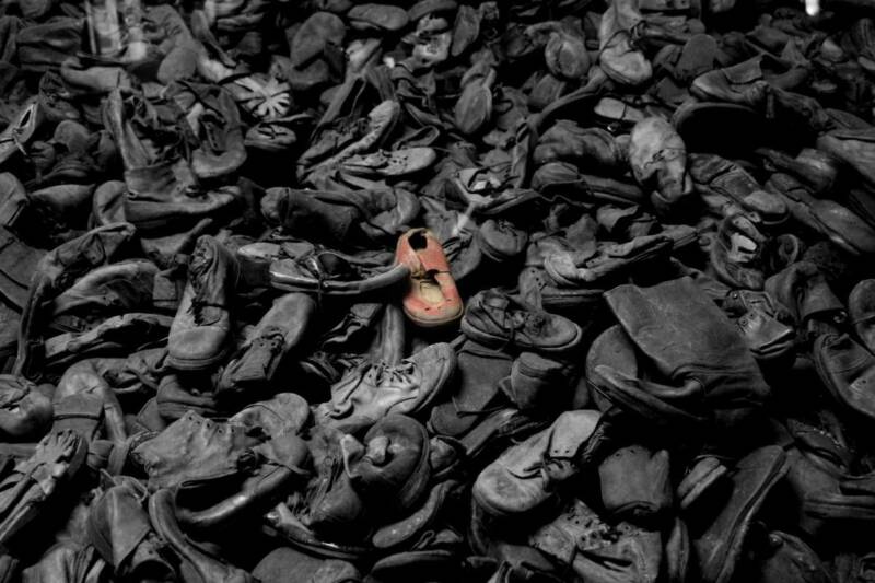 Image of large amount of worn-out and tattered shows. The image is black and white, except for one pair of shoes in the centre which are brown. Image credit: Paul Beattie ©