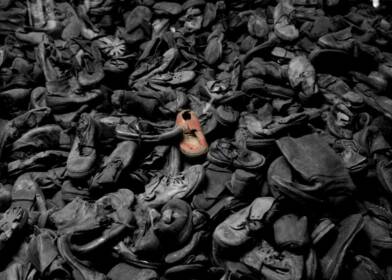 Image of large amount of worn-out and tattered shows. The image is black and white, except for one pair of shoes in the centre which are brown. Image credit: Paul Beattie ©