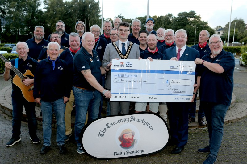 Mayor of Causeway Coast and Glens, Councillor Ciarán McQuillan and Councillor Steven Callaghan, pictured with The Causeway Shantymen as they present a cheque to John Martin, RLNI, with money raised over the summer from their open rehearsals across the Borough.